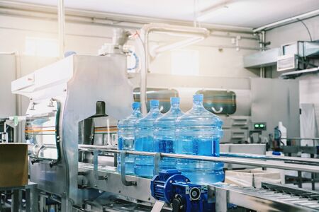 Industrial interior of water plant production. Conveyor belt, filled bottles on beverage factory,...