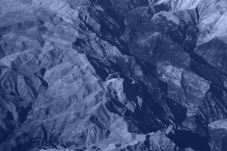 Phantom blue toned mountain panorama background, aerial view from airplane window.