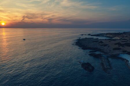 Sunset in Cyprus. Aerial view of mediterranean sea and rocky coastline in summer evening, drone...