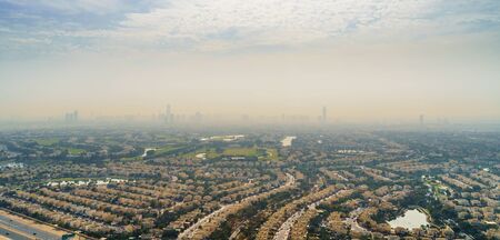 Aerial Dubai panorama with villas and houses of local residents on foreground and high-rise skyscrapers buildings in morning dusk on background, United Arab Emirates.の写真素材