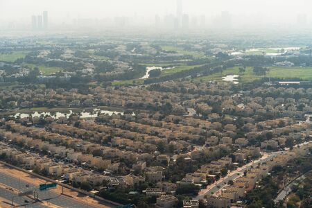 Aerial view of Dubai with villas and houses of local residents on foreground and high-rise skyscrapers buildings in morning dusk on background, United Arab Emirates.の写真素材