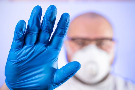Hand in medical mask with stop gesture. Mean in medical mask. Quarantine due to coronavirus...