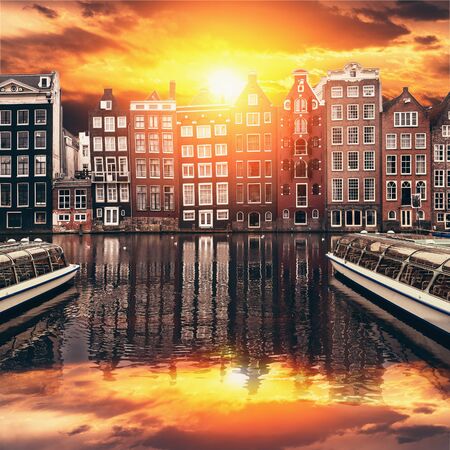 Amsterdam Netherlands dancing houses reflected in Amstel river at dramatic sunset, old european city.の写真素材