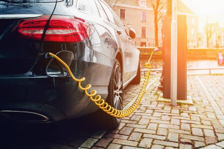Charging electric car in public charger station on European street.の写真素材