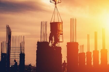 Construction site with scaffolds and workers silhouettes at sunset sky background. Modern industry development concept.の写真素材