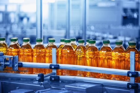 Beverage factory, Conveyor belt with juice in bottles, Industrial Interior in blue color, food and drink production line process.の写真素材