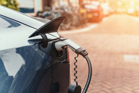 Charging modern electric car on city street, close up. Innovation and future transportation.