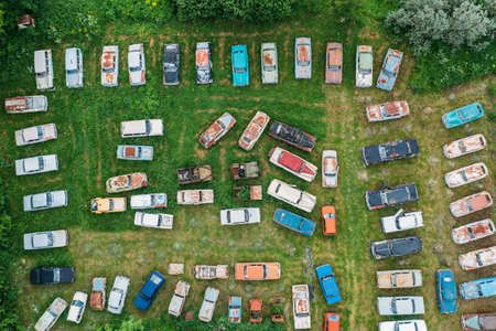 Old retro rusty abandoned cars in green grass, aerial top view from drone above cemetery of vintage...