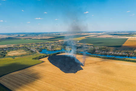 Farm field in fire, aerial view. Burning agricultural rye field with smoke.の写真素材