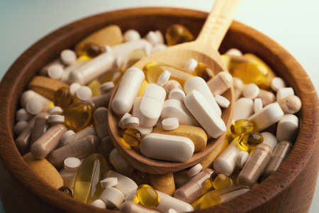 Medicine pills, tablets and different drugs in wooden bowl with spoon.