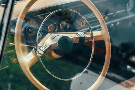 Steering wheel of old abandoned rusty car, view through glass with reflection.の写真素材