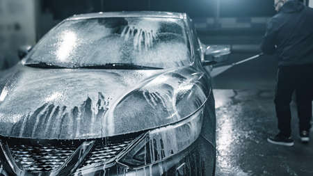 Car washing at night. Man cleaning his car using high pressure water at self-service.の写真素材