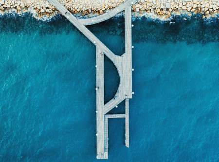 Aerial top view of wooden pier at Limassol Molos Park and blue sea surface.