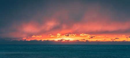 Panoramic shot of dramatic sunset cloudy sky over sea or ocean in stormy windy weather.