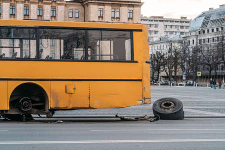 City bus with broken wheel stands on urban road.