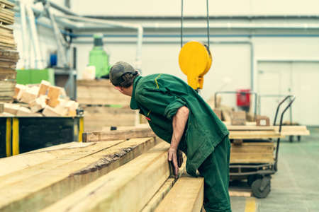 Unrecognizable worker in timber workshop at woodworking plant.の写真素材