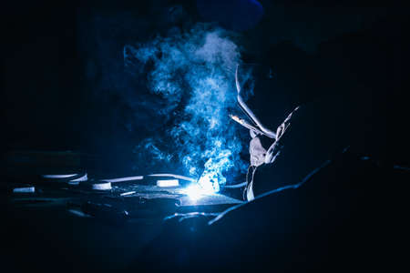 Welder at works close up. White flashes and welding smoke. Metalwork process.の写真素材