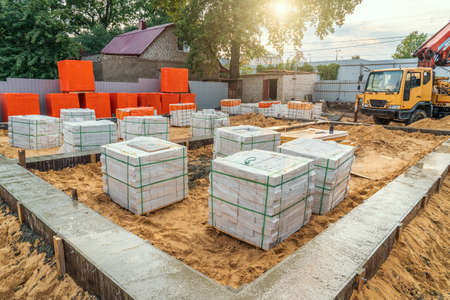 Freshly poured strip foundation at construction site and building materials for construction of new...