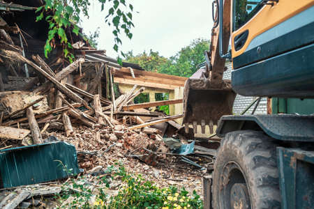 Demolition of house. Broken walls of old building and excavator at site of future construction.の写真素材