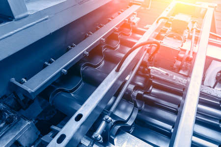 Industrial background. Metal sheet forming machine conveyor belt in factory. Roof tile manufacturing.の写真素材