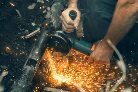 Worker cuts gas pipe with grinder, close up.