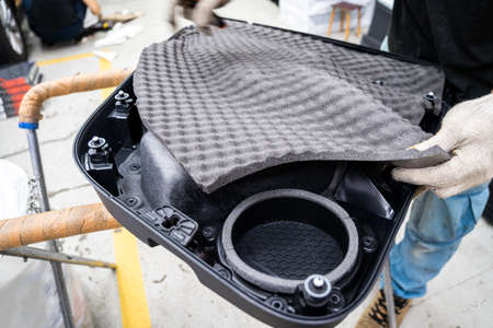 Worker in service shop installs soundproofing material on inside of car door card. Process of noise insulation for auto.の写真素材