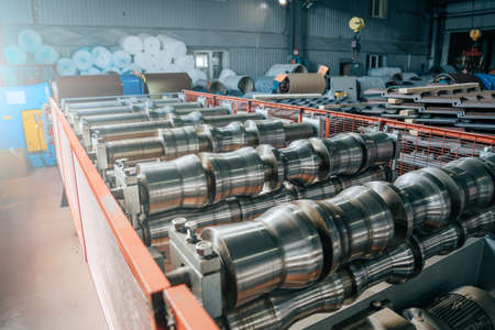 Production line of metal tile for roof. Steel forming machine in metalwork factory workshop. Metal sheet profiling machine.の写真素材