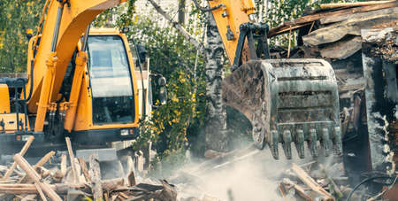 Demolition of old house. Excavator breaks building for new housing.の写真素材