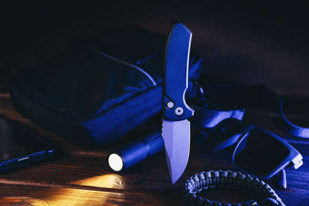 Everyday carry or EDC survival tactical set for modern man in blue light. Pocket automatic knife, flashlight, paracord and bag.の写真素材