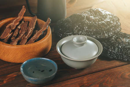 Brewed Dried Chinese Lingzhi in bowl and sliced pieces of Ganoderma Lucidum or Reishi mushroom in plate on wooden table. Asian herbs for health.の写真素材