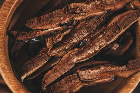 Sliced on pieces Ling Zhi Natural Chinese Herb or Reishi Mushroom, Ganoderma in wooden plate close up top view. Organic herbal medicineの写真素材