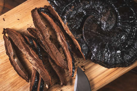 Sliced on pieces Ling Zhi Natural Chinese Herb or Reishi Mushroom, Ganoderma on kitchen wooden desk....