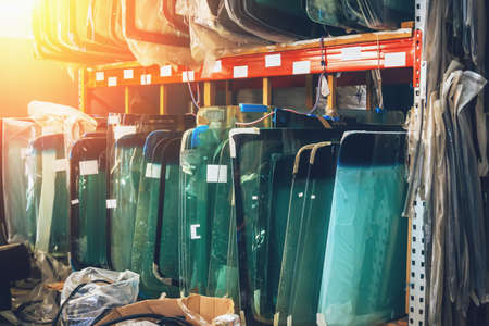 Many windshields for cars on service station shelves ready to install or replace broken glass with...