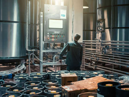 Brewer controlling automatic brewing process in modern microbrewery manufacturing craft beer.