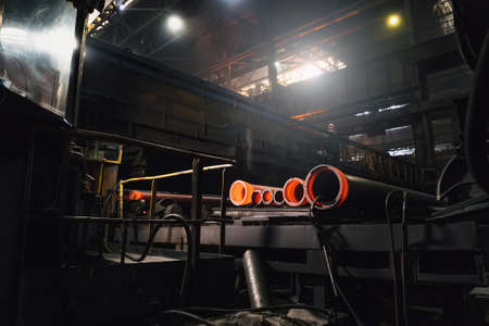 Freshly cast hot cast iron pipes at smelter. Manufacture of pipes for water, gas or oil.