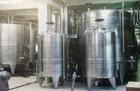 Typical steel barrels for wine fermentation in winery factory.