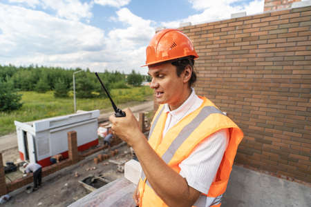 Foreman inspector or construction worker in hardhat portrait. Engineer in helmet with walkie-talkie...
