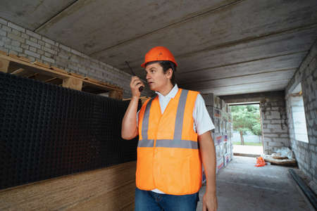 Foreman inspector or construction worker in hardhat portrait. Engineer in helmet with walkie-talkie...