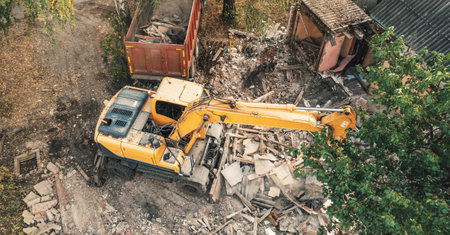 Demolition of old house, aerial view. Excavator breaks building for new housing.