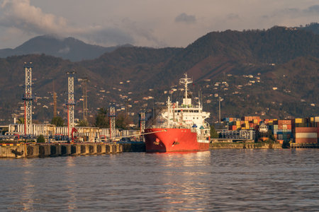 Red tanker ship at terminal port. Transportation, logistics and unloading of gas or oil in industrial harbor.の写真素材