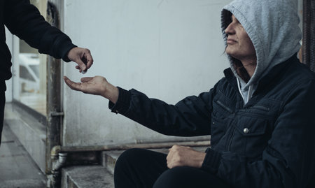 Stressed hungry homeless man sitting on city street waiting for help and money.の写真素材