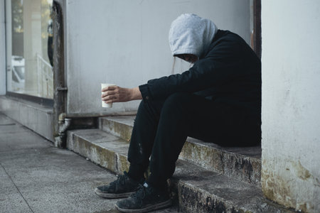 Homeless man sits on steps and asks for help and money.の写真素材