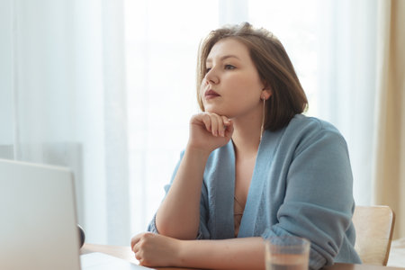 Plus size woman thinking and having break while working at home. Distance remote work concept.