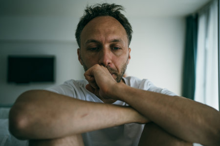 Sad middle age man alone at home. Emotional stress, burnout and midlife crisis concept.の写真素材