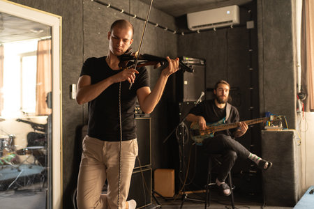 Music band repetition. Violinist and guitarist tune musical instruments.の写真素材