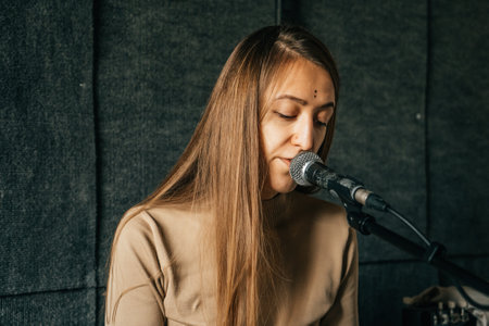 Woman singer play piano and sing in microphone, recording song in sound record studio.の写真素材