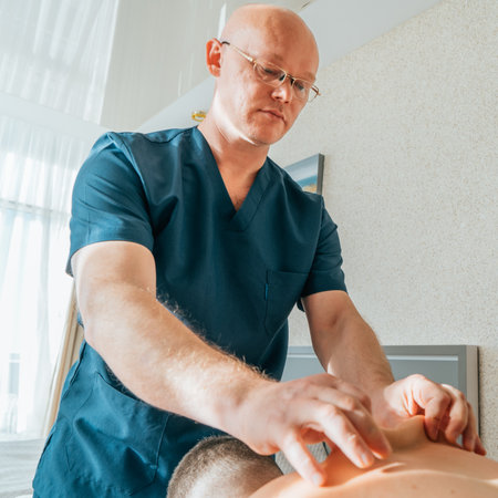 Massage therapist with strong hands and fingers kneads muscles of athlete back after injury or muscle sprain, therapeutic and pain relieving massage.の写真素材