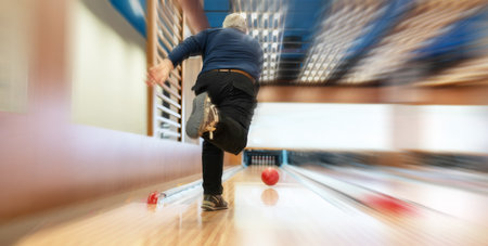 Senior man in midst of bowling captured with blurred motion effect, emphasizing speed and movement.の写真素材