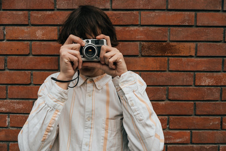 Enthusiastic male photographer framing shot with his classic vintage old camera in city.