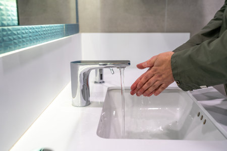 Hands Washing Hands Under Modern Faucet Close up.の写真素材